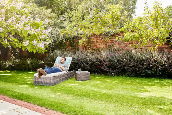 Man laying down on a sun lounger on freshly cut grass