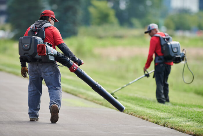 Professional landscaper using Toro Revolution 60V Blower Cannon and backpack on roadside path