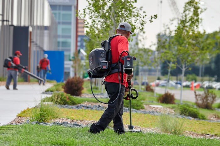 Landscape contractor using Toro string trimmer and battery backpack for professional outdoor maintenance